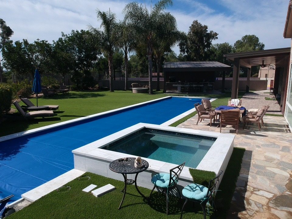 Backyard built by Catalina Hardscapes — stone patio, artificial turf and pool surround